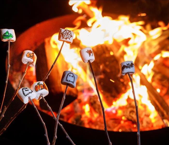 marshmellows with halloween images on them above a roaring bonfire